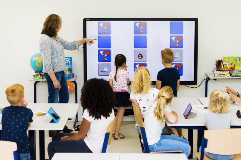 Kinderen in een klaslokaa voor een digibord met apps